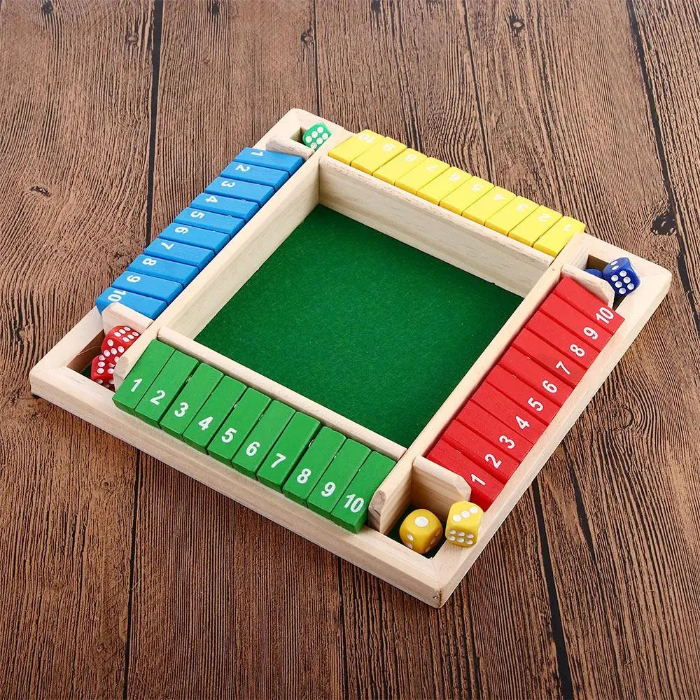 A wooden shut the box dice game set with colored dice and a green board on a wooden surface.