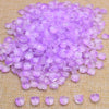 A pile of small, translucent purple glass beads scattered on a beige surface.