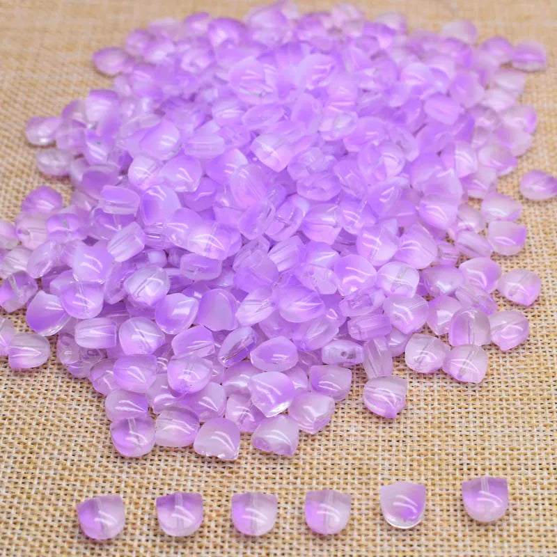 A pile of small, translucent purple glass beads scattered on a beige surface.