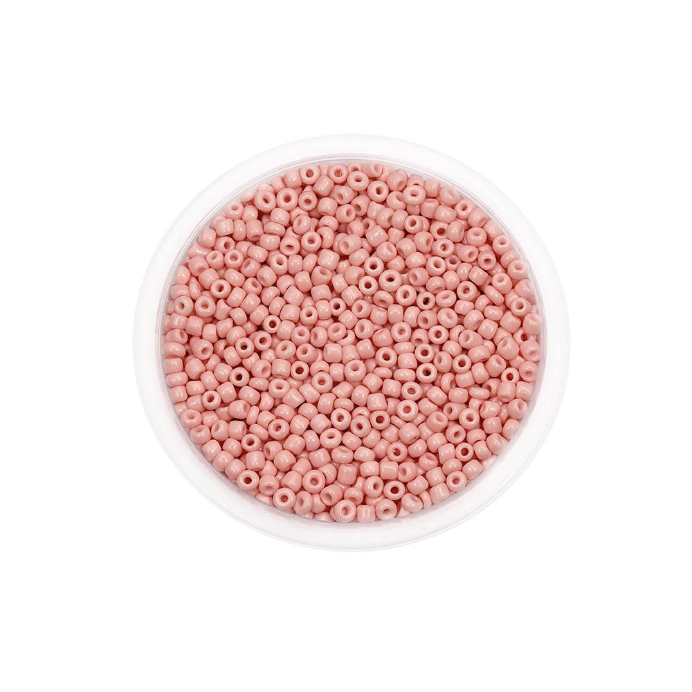 A clear container filled with pink round glass seed beads for jewelry making.