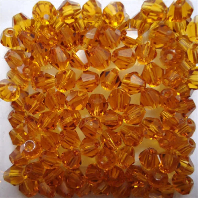 A close-up view of faceted, golden-orange glass bicone beads used for jewelry making.