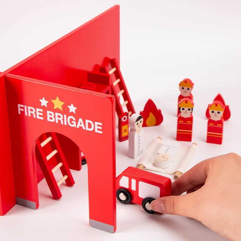 A red wooden fire brigade building toy set with a ladder and figures being held by a hand.
