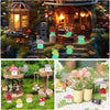 A collection of glow-in-the-dark resin miniature mushrooms in various colors displayed on a mossy fairy garden setting.