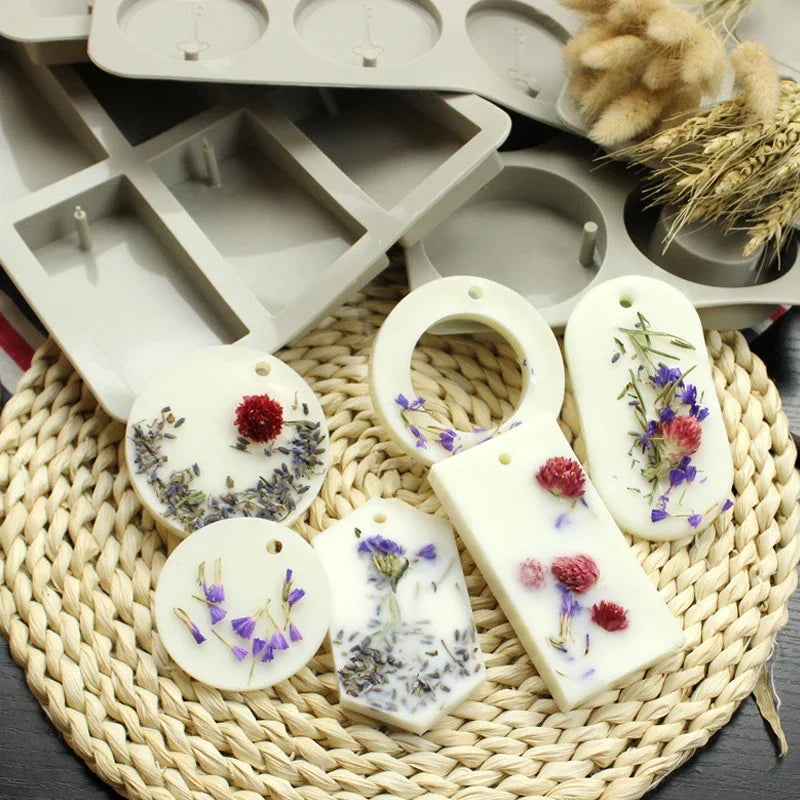 A collection of hexagonal silicone molds for handmade soap and candles resting on a woven mat.