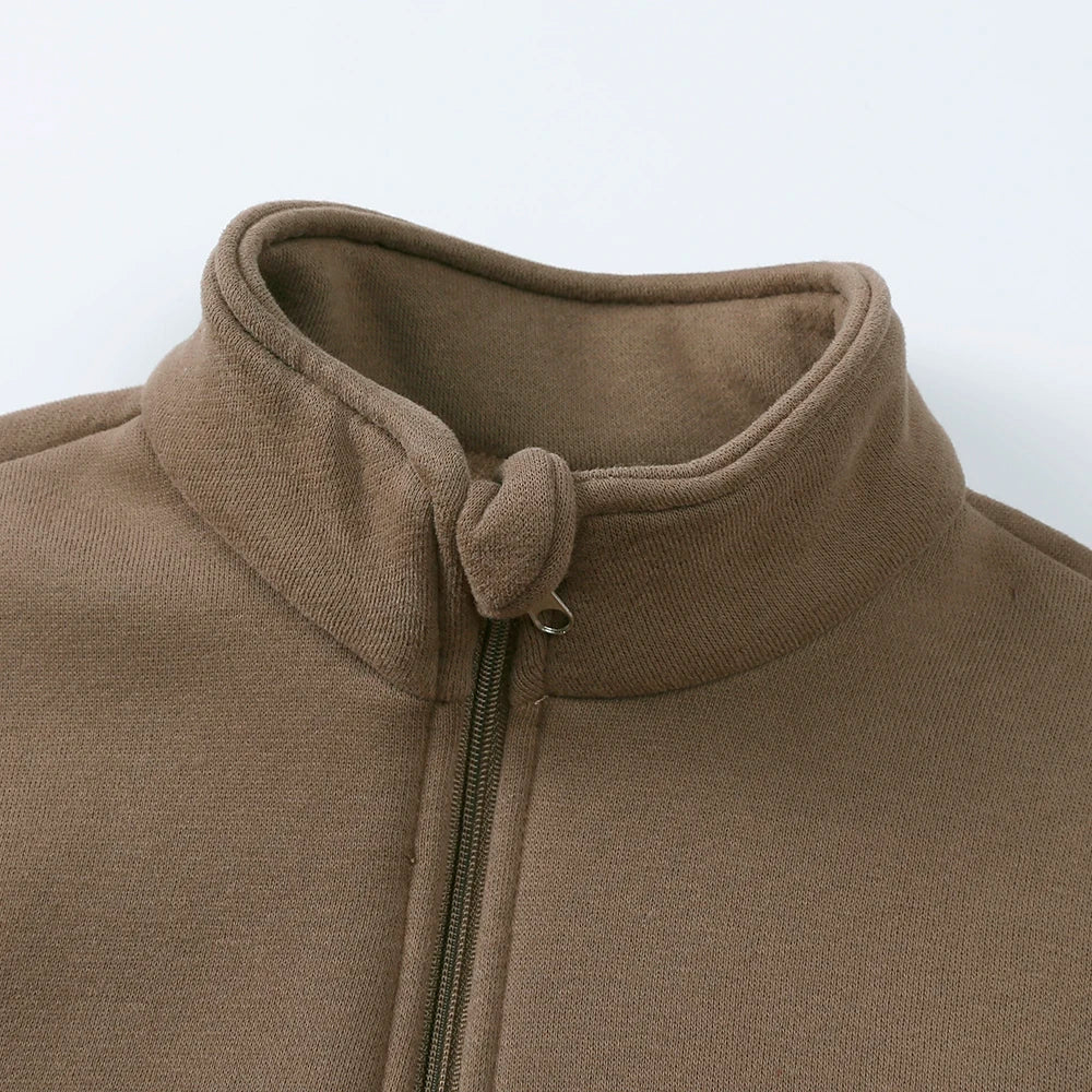 A close-up of a brown fleece hooded jacket with a ribbed collar and a zipper detail.