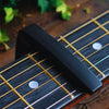 A black aluminum alloy quick-change guitar capo is placed on the fretboard of a dark wood guitar.