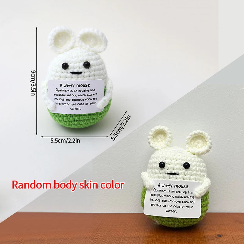 A white crocheted bunny doll with black eyes and a green felt tag featuring an inspirational quote.