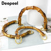 A pair of natural bamboo-style bag handles with gold-colored hardware displayed on a white background.