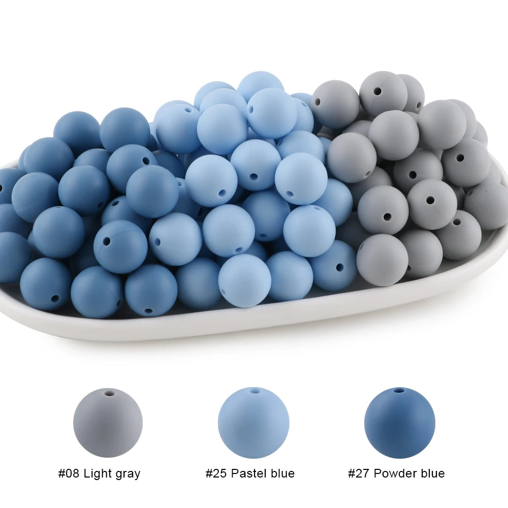 A collection of round silicone beads in light gray, pastel blue, and powder blue colors.