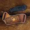 A handcrafted leather knife sheath with a belt loop resting on brown fur.