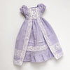 A lavender dress set for a doll featuring lace trim and ruffled details.