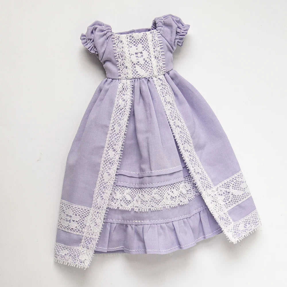 A lavender dress set for a doll featuring lace trim and ruffled details.