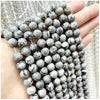 A hand holds a strand of natural stone beads for DIY jewelry making featuring various colors and patterns.