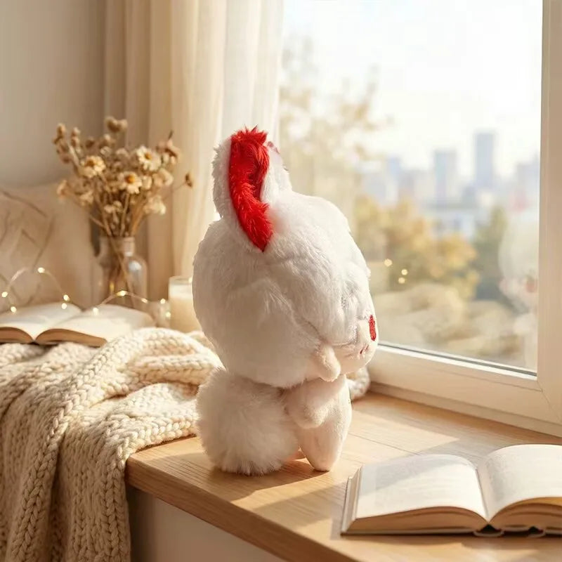 A fluffy white anime plush toy with red ears sits on a wooden shelf next to a book and a knitted blanket.