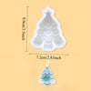 A white silicone Christmas tree shaped mold with a star topper and a small blue frosted Christmas tree.