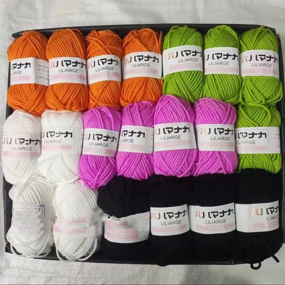A collection of various colored acrylic wool yarn skeins packaged in a black box for knitting and crochet projects.