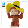 A collectible figure of Curious George wearing a yellow cowboy hat and brown body.