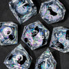 A collection of handmade liquid core resin dice set with sharp edges, featuring various geometric shapes and iridescent color
