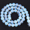 A strand of round, translucent light blue and white sea sediment jasper and turquoise beads for jewelry making