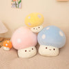 A set of soft, colorful mushroom plush pillows in yellow, pink, and blue sitting on a beige fabric.