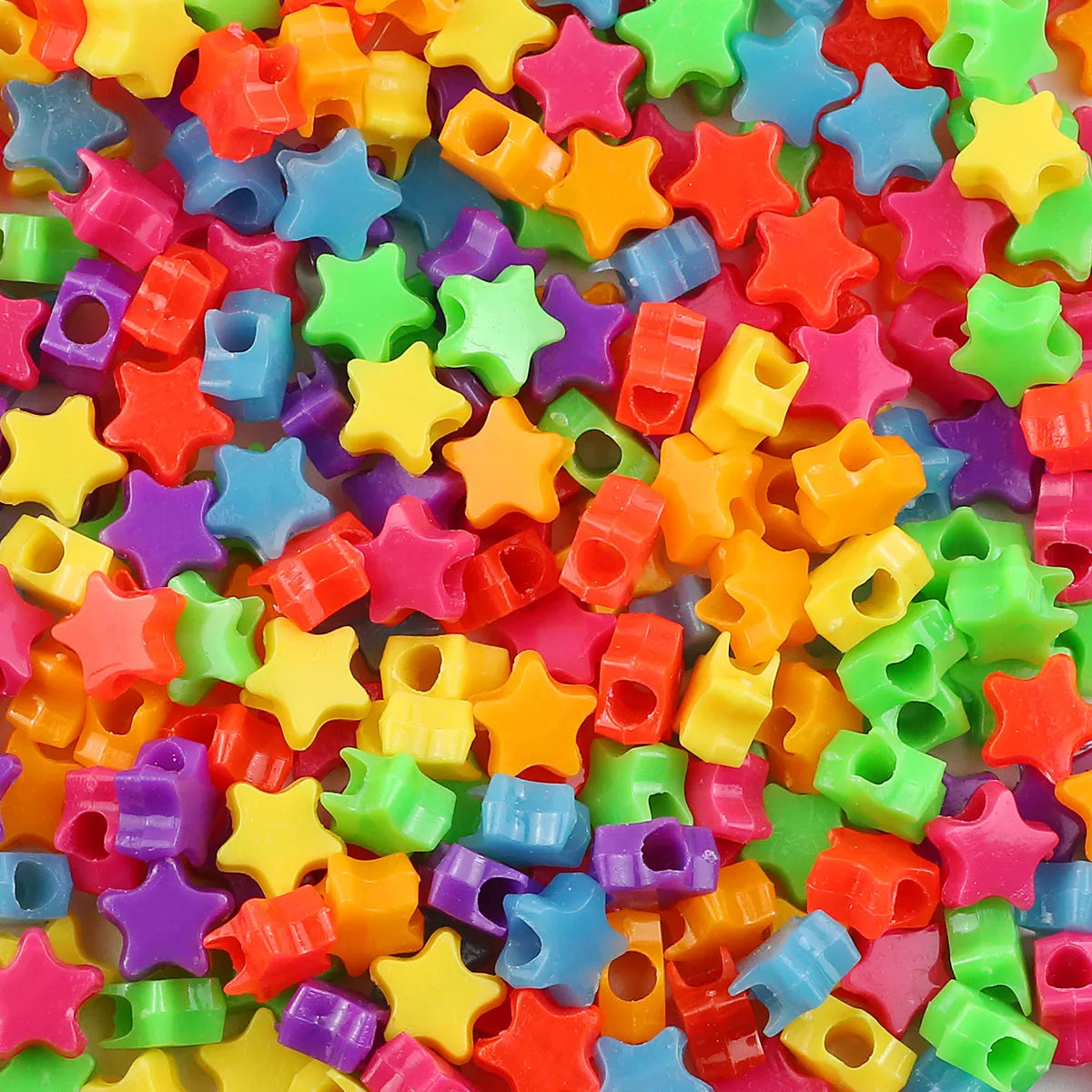 A close-up of a pile of multicolor pony beads in various shapes and colors for jewelry making and crafts.