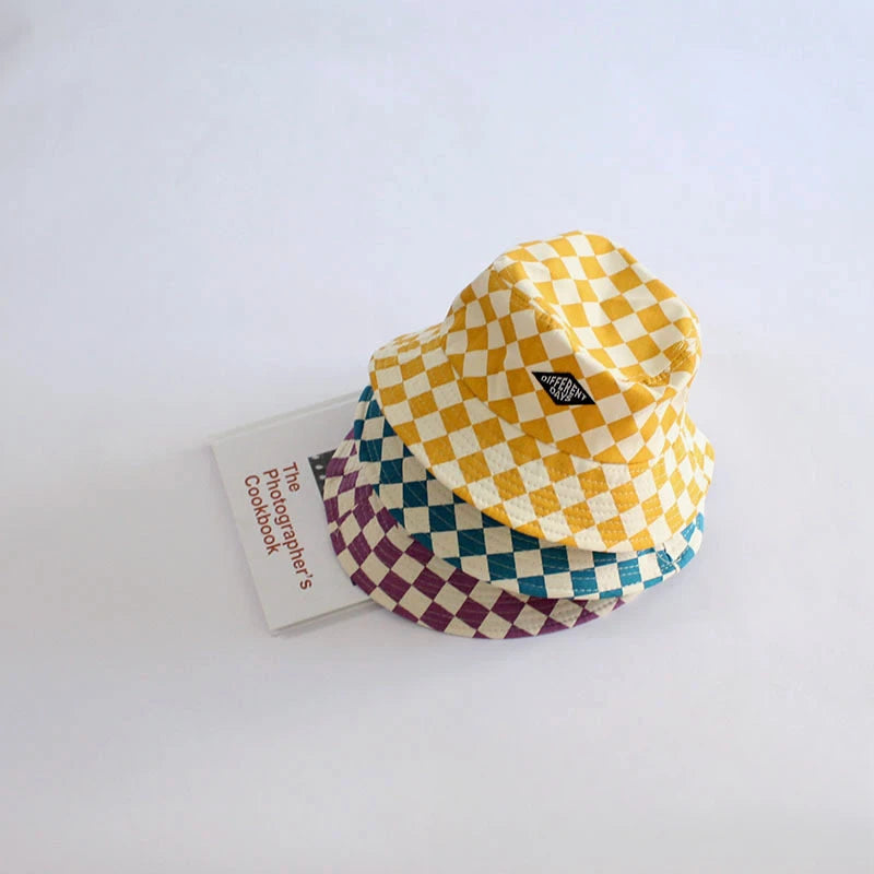 A stack of yellow and purple checkerboard bucket hats made of soft cotton.