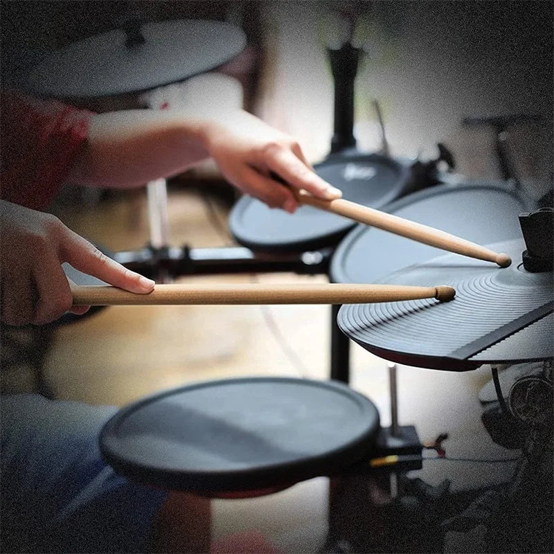 A pair of maple wood drumsticks being held by a person in a close-up shot.