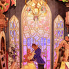 A wooden puzzle kit depicting Beauty and the Beast figures in a detailed stained glass style scene.