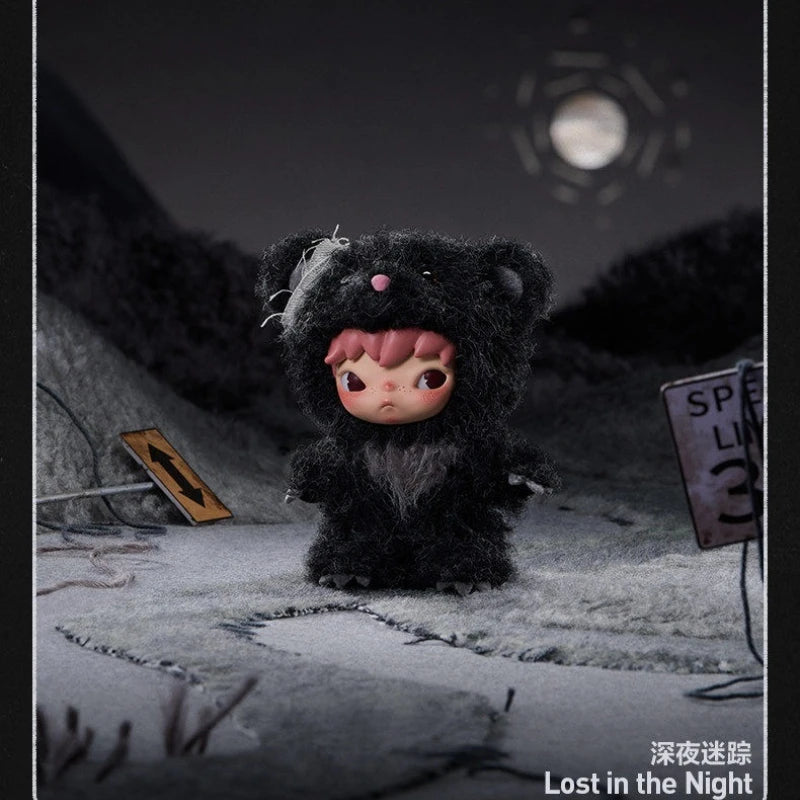 A dark, fluffy black plush doll with pink accents sits in a snowy outdoor setting under a night sky.