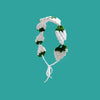 A white strawberry crochet headband with a wide elastic band against a teal background.