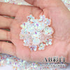 A hand holds a cluster of iridescent pink and purple sakura flower crystal glass beads for jewelry making