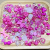 A variety of mixed pink and purple acrylic loose beads for jewelry making displayed on a wooden board.