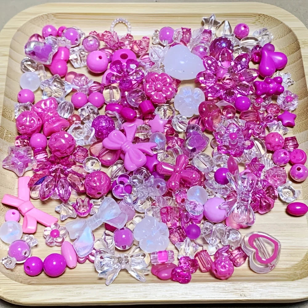 A variety of mixed pink and purple acrylic loose beads for jewelry making displayed on a wooden board.