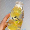 A hand holds a clear glass bottle filled with yellow liquid and slices of citrus fruit, labeled Chiboki drink cup toy.