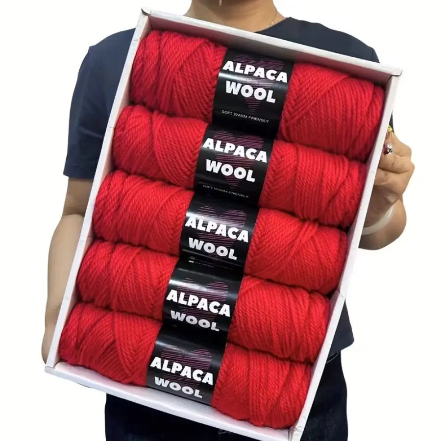 A pack of five red alpaca wool yarns for knitting and crochet displayed in a white box.
