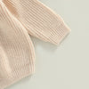 A close-up of a light beige knit long sleeve sweater for kids.