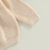 A close-up of a light beige knit pullover sweater with a textured stitch pattern.