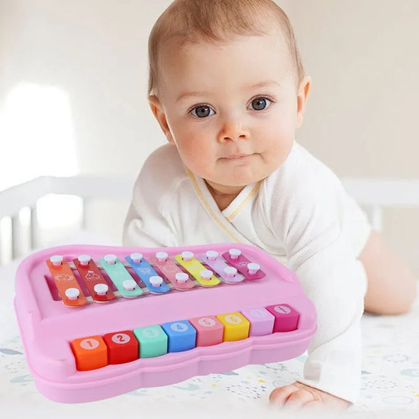 A baby is holding a pink Montessori music instrument set for toddlers with colorful plastic keys.