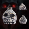 A ceramic Aztec skull whistle with intricate carvings shown in three views against a dark background.
