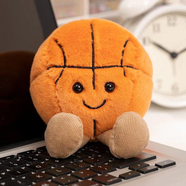 An orange plush sports ball cushion resting on a laptop keyboard.