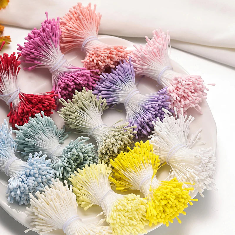A collection of mini pearl stamen floral decorations in various shades of pink, purple, green, and yellow arranged on a white
