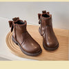A pair of brown leather ankle boots with bow-knot detailing and a side zipper resting on a wooden surface.