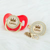 Personalized rose gold crown pacifier and clip set featuring a red silicone ring and a gold crown charm