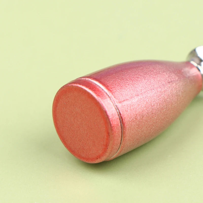 A miniature rose gold alloy kettle with a smooth, rounded body is shown against a light green background.