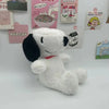 A white Snoopy cartoon plush toy pillow is displayed in front of various themed posters.