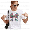 A woman models a white t-shirt featuring a large floral letter bow iron-on patch on the chest.