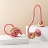 A pink silicone teething toy with a curved handle and ring is displayed on a white surface.