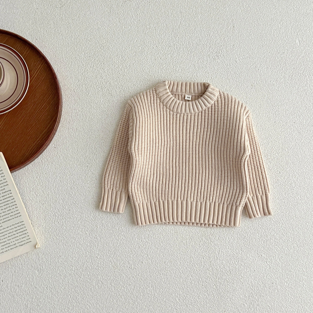A beige knit baby pullover sweater for boys and girls displayed on a white surface.