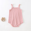 A light pink, ribbed cotton strappy romper for babies with a small wooden animal charm.
