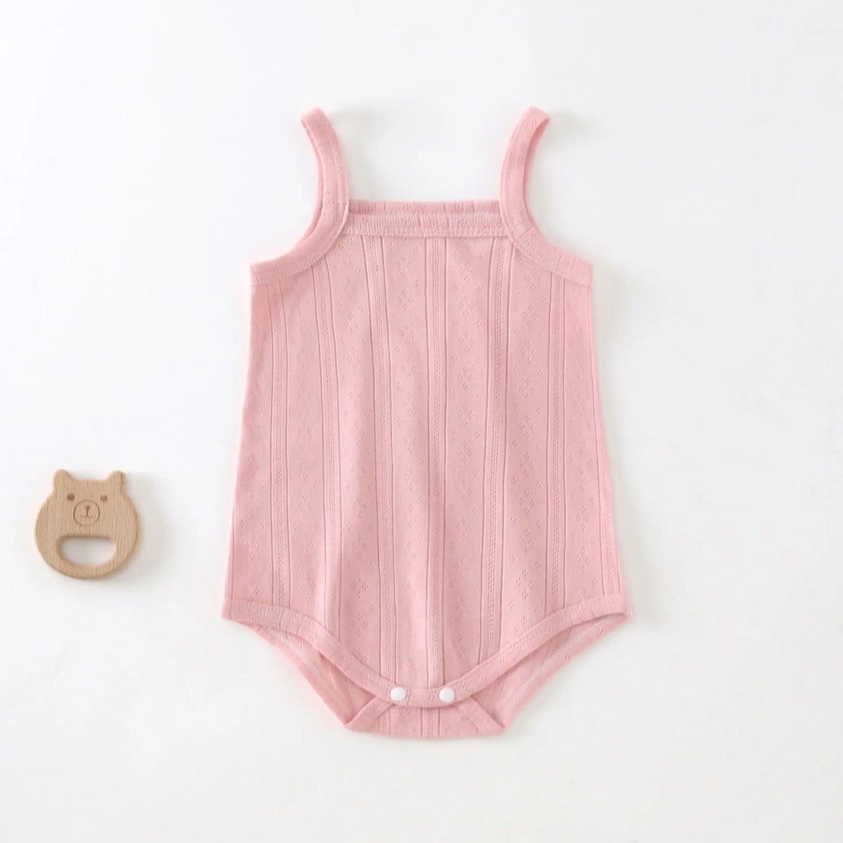 A light pink, ribbed cotton strappy romper for babies with a small wooden animal charm.